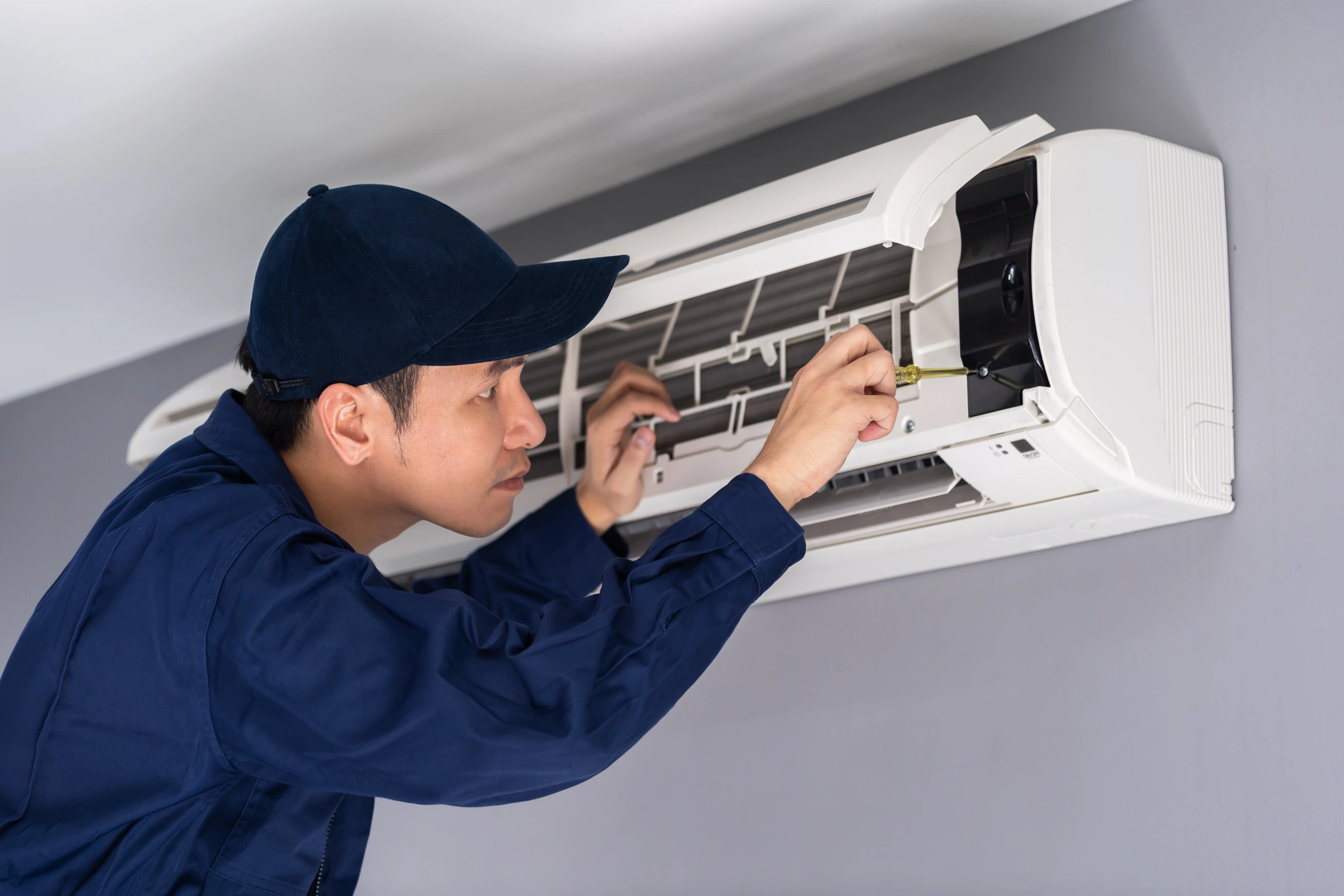 Technicien intervenant sur une unité de climatisation murale