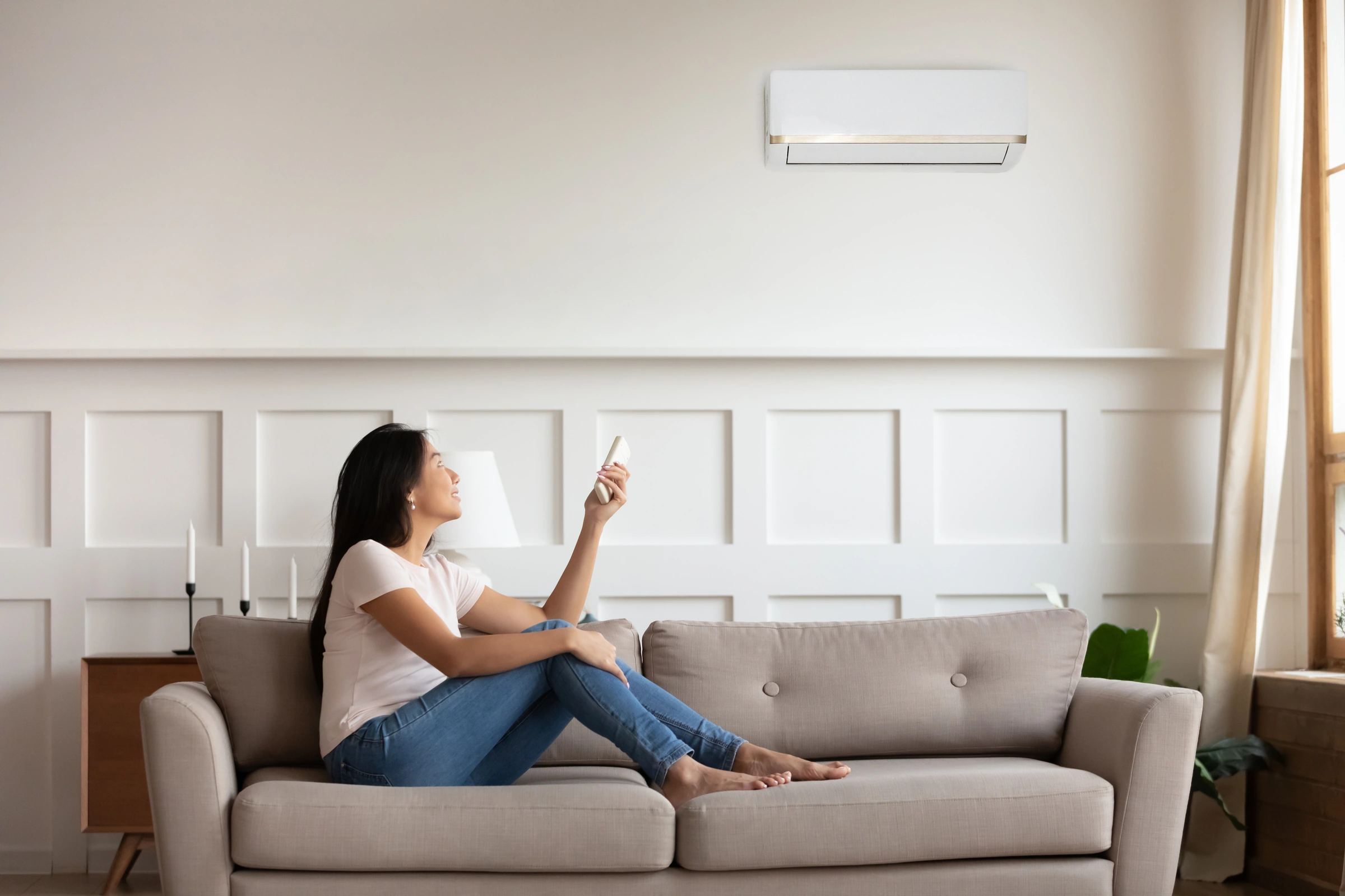Réglage d’un climatiseur avec une télécommande dans un salon