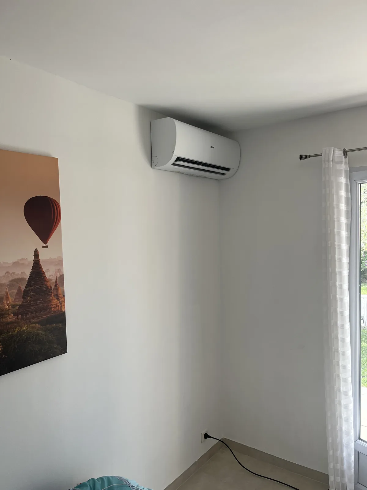 Même pièce après installation d’un climatiseur Haier en hauteur entre le tableau et la fenêtre