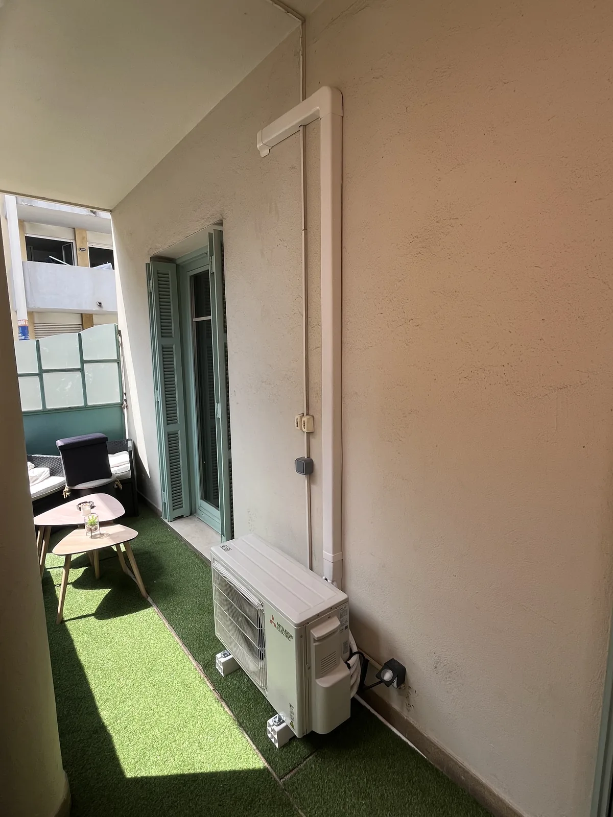 Installation de climatisation sur un balcon avec groupe Mitsubishi Electric et goulotte montant jusqu’au plafond