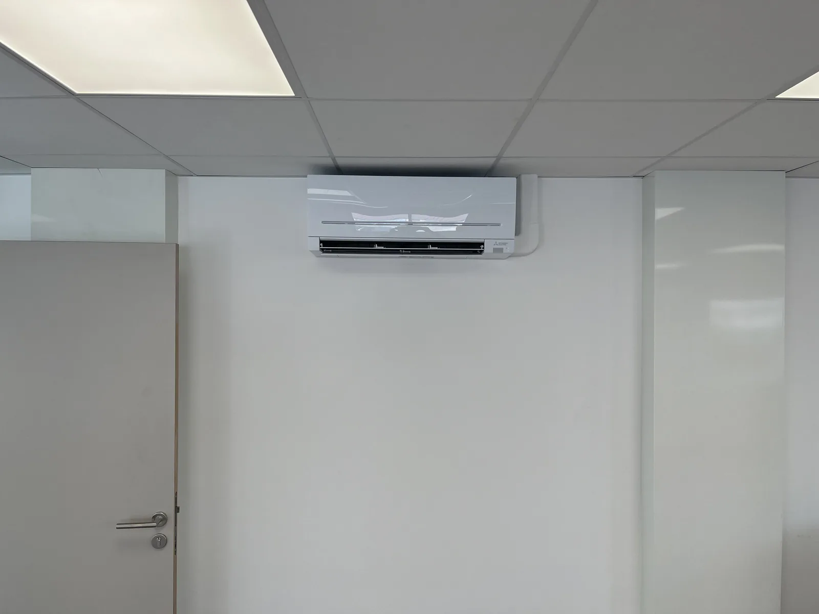 Climatiseur mural Mitsubishi Electric installé sous un plafond en dalles