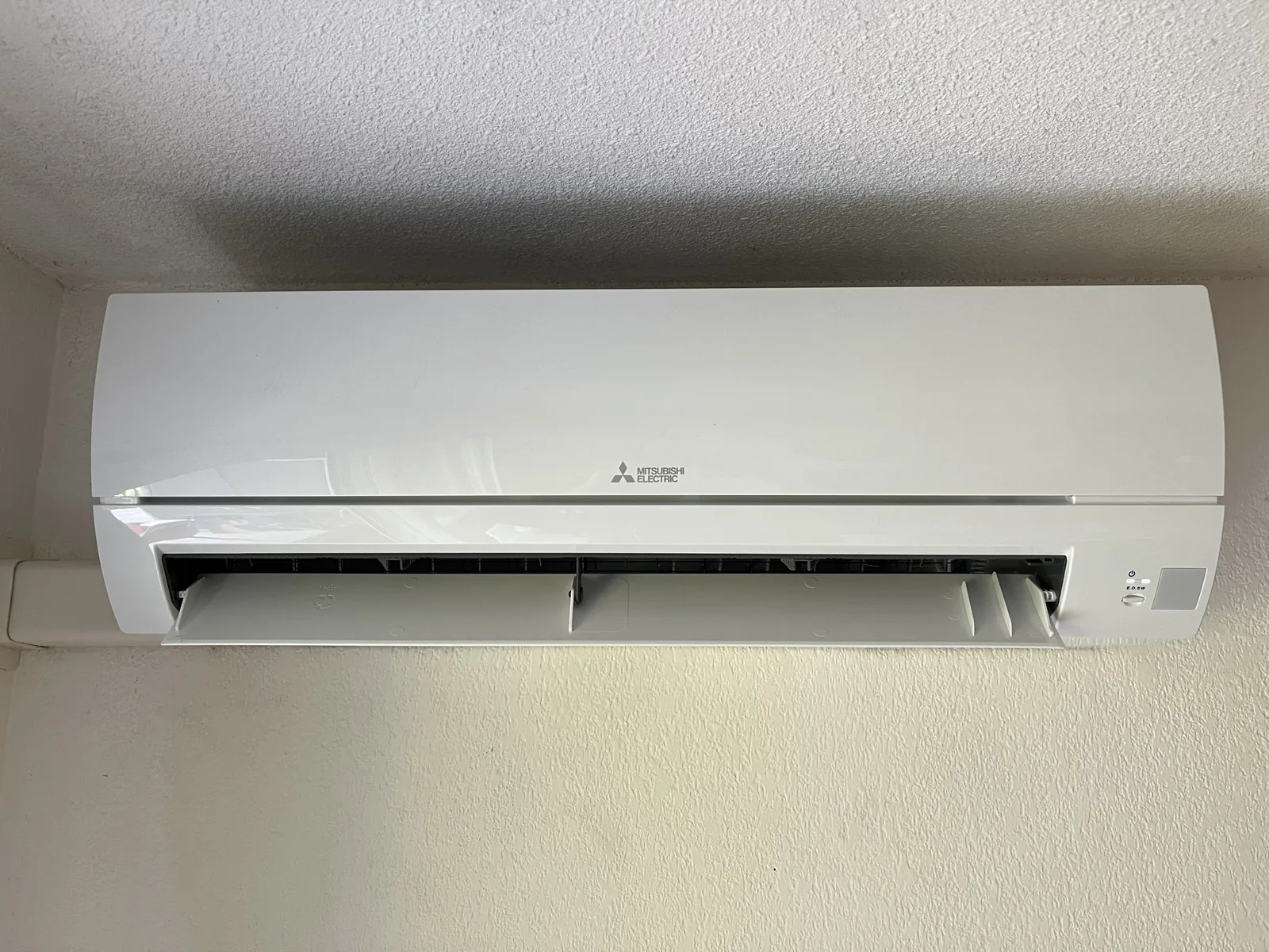 Unité intérieure Mitsubishi Electric fixée en partie haute d’un mur clair